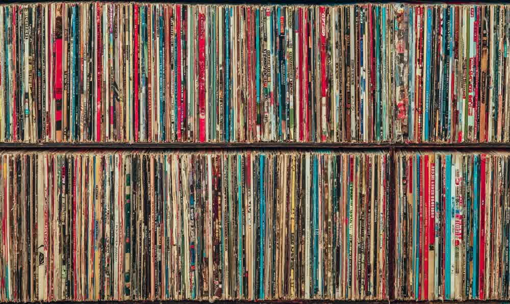 A carefully organized record collection with album sleeves, cleaning brush, turntable, watch, and denim jacket