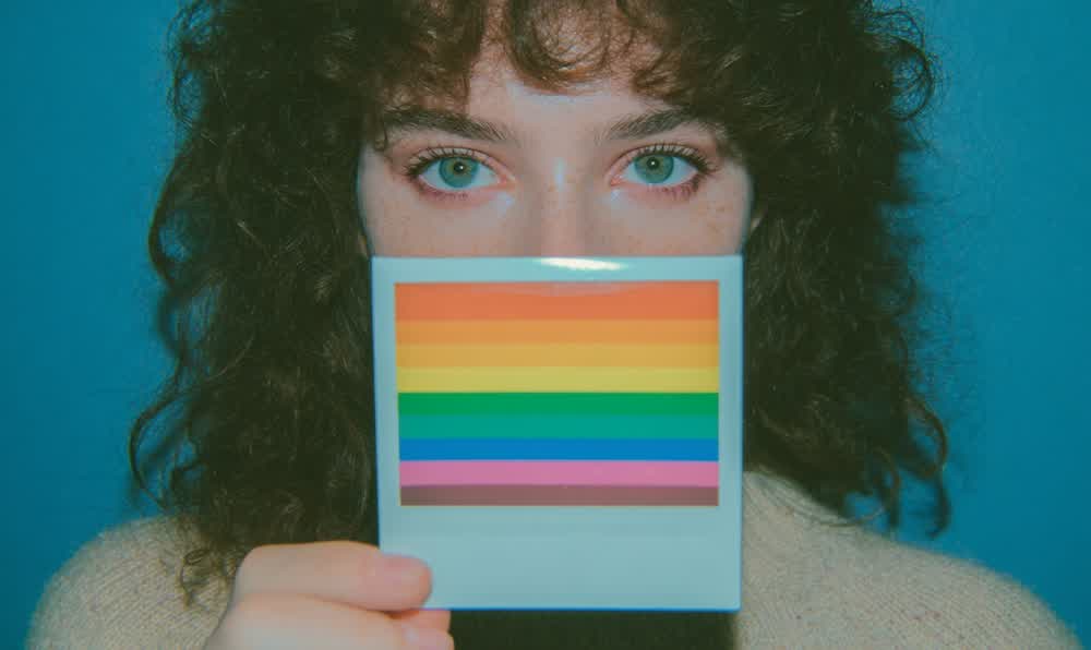 Instant Polaroid photographs developing beside a retro camera, sunglasses, and a leather jacket in warm light