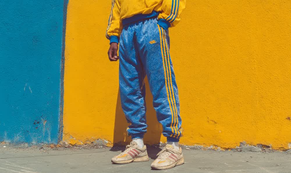 Retro sportswear outfit with track jacket, sneakers, striped socks, watch, sunglasses, and bold 80s-90s color blocks