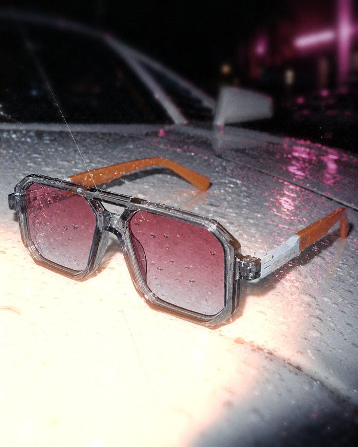 Pink Haze Sunglasses 1984 close up on a wet car hood at night