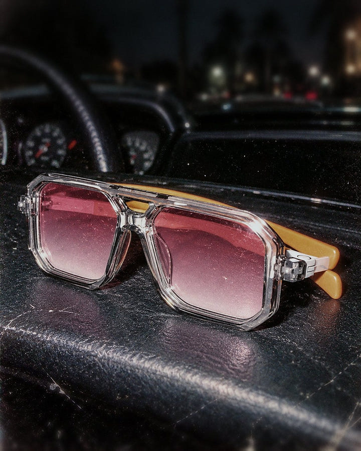Pink Haze Sunglasses 1984 on a car dashboard at night