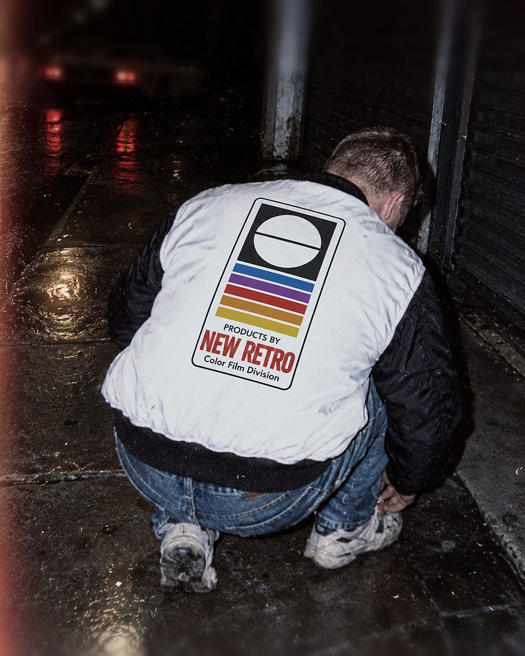 Color Film Bomber 1983 crouched on a wet sidewalk at night